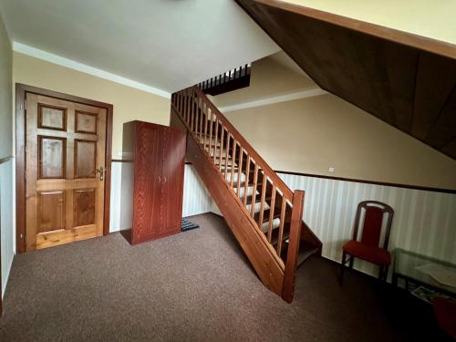 a wooden staircase with a wooden door and a red chair at Villa Daniela in Úvaly