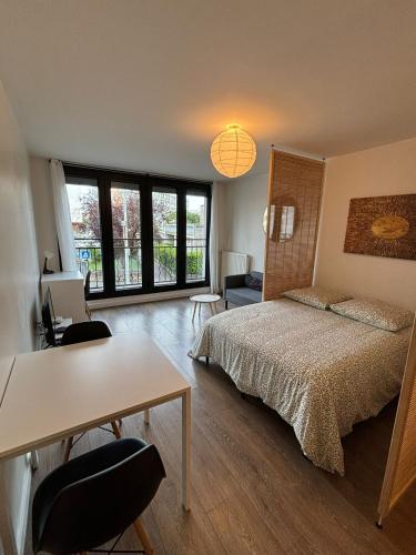 une chambre avec un lit, un bureau et une table dans l'établissement charmant studio sur Romainville, à Romainville