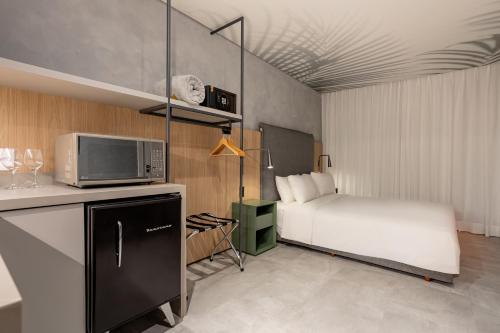 a small bedroom with a bed and a microwave at Brava Mundo Hotel Boutique OFICIAL in Itajaí