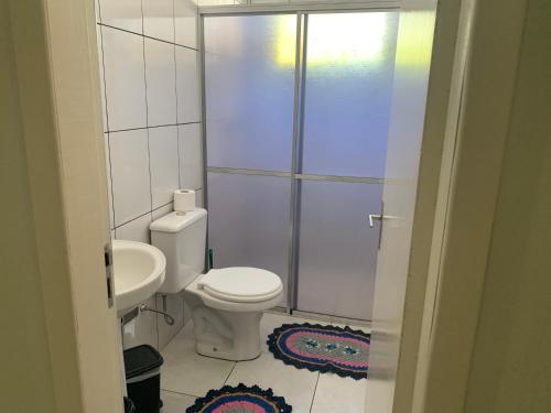 a white bathroom with a toilet and a sink at Espaço e conforto 1 in Guaíra