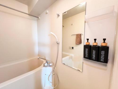 La salle de bains est pourvue d'un miroir et d'une baignoire. dans l'établissement Shinjuku NZO Apt, à Tokyo