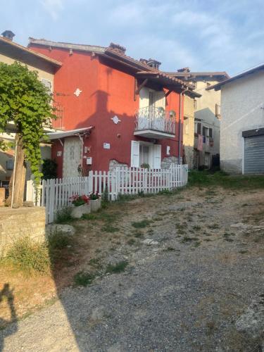 a red house with a white fence in front of it at JOLIE PETITE MAISON chez Barbara in Garbagna