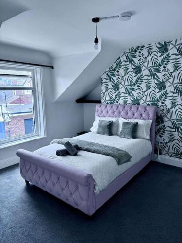 a bedroom with a bed with a purple headboard and a window at Blessed Princess House With Free Parking in Sunderland