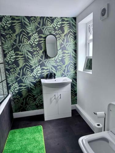 a bathroom with a sink and a green wallpaper at Blessed Princess House With Free Parking in Sunderland