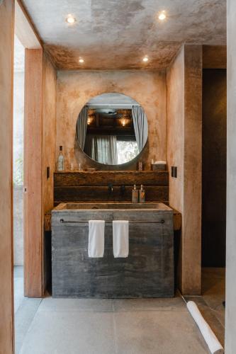 a bathroom with a wooden vanity with a mirror at Nômade Temple Tulum in Tulum