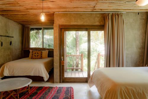 a bedroom with two beds and a sliding glass door at Nômade Temple Tulum in Tulum