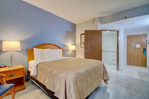 a bedroom with a bed and a walk in shower at Quality Inn & Suites CVG Airport in Erlanger