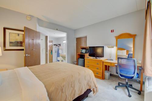 a bedroom with a bed and a desk and a computer at Quality Inn & Suites CVG Airport in Erlanger