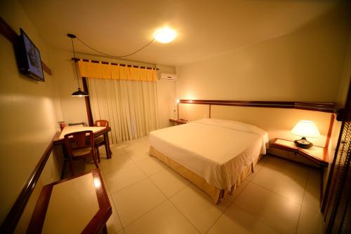 una camera da letto con un letto, un tavolo e una scrivania di Hotel Águas Claras a Santa Cruz do Sul