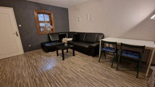 un salon avec un canapé en cuir noir et une table dans l'établissement Charmant appartement lumineux proche du centre ville, à Strasbourg