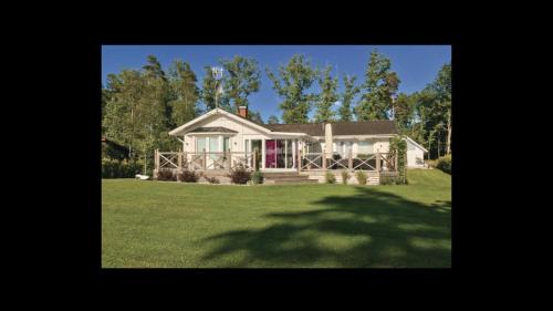a house on a grassy field with a tree at Beautiful lake house with first class view ! in Ljungby