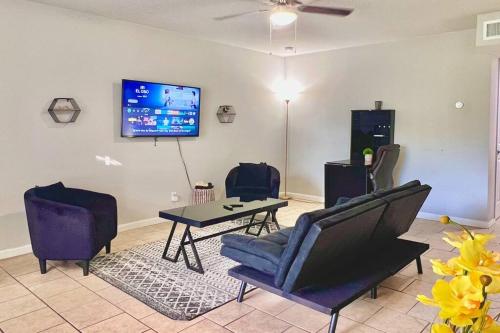 a living room with chairs and a tv on a wall at KING SUITE 2BR Home w FAST WiFi, & WFH Desk in San Antonio