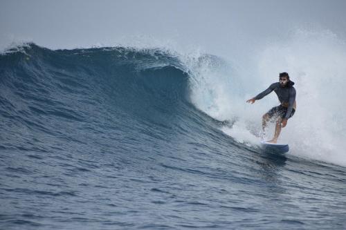 a man riding a wave on a surfboard in the ocean at Finimas Residence in Thimarafushi