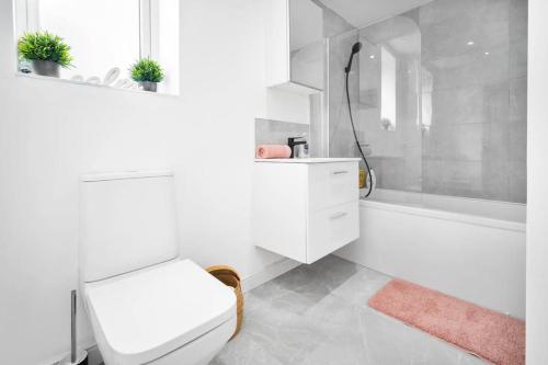 a white bathroom with a toilet and a bath tub at Family Contractors 3 bed house free parking sleeps7 in Bilston