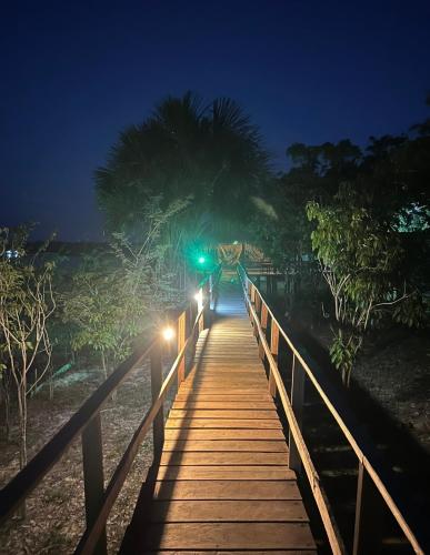 a wooden bridge with lights on the beach at night at Amazônia LODGE Exxperience in Manaus