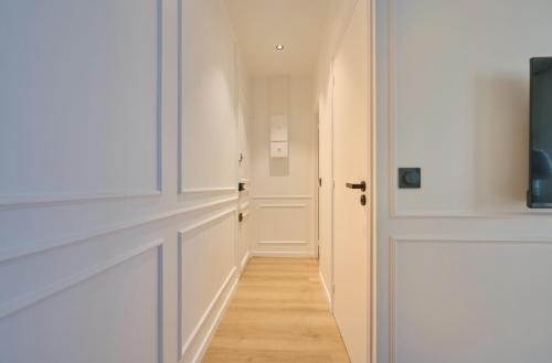 un couloir avec une porte blanche et un plancher en bois dans l'établissement Eiffel Appartement, à Paris