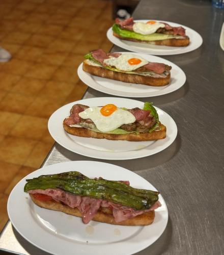 four white plates with sandwiches with eggs on them at Hotel Restaurante Rio Cuervo in Vega del Codorno