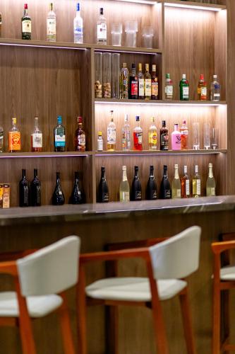 a bar with two chairs and bottles of alcohol at Brava Mundo Hotel Boutique OFICIAL in Itajaí