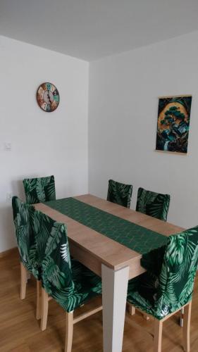 a dining room table with green chairs and a clock on the wall at Apartament Tereska in Duszniki Zdrój