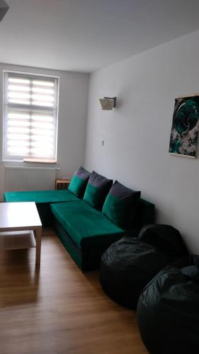 a living room with a green couch and a table at Apartament Tereska in Duszniki Zdrój