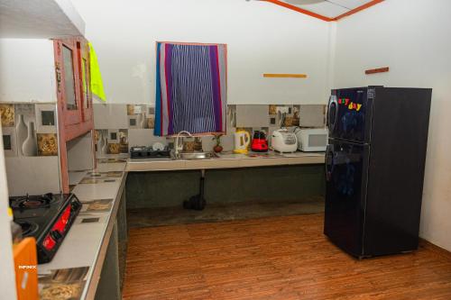 a kitchen with a black refrigerator and a counter at Hanguk Villa Mirissa in Mirissa