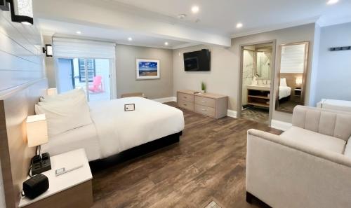 a bedroom with a white bed and a couch at Colonial Hotel & Suites in Grand Bend