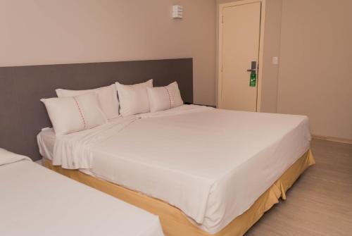 a bedroom with two beds with white pillows at Abba Hotel in Betim
