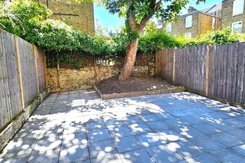 a tree in a garden with a wooden fence at Flat in Queens Park in London