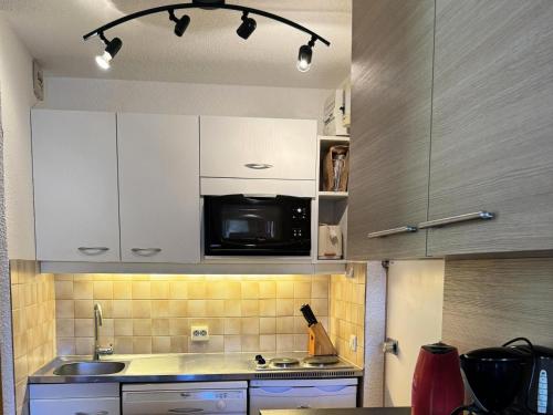 a kitchen with white cabinets and a microwave at Résidence Pierre De Soleil - Studio cosy · Skis aux pieds MAE-3617 in Mâcot La Plagne
