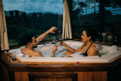 un hombre y una mujer sentados en una bañera en Sítio Mar de Nuvens Chalés Morro da Igreja, Urubici, SC., en Urubici