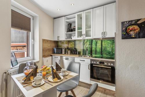 a kitchen with white cabinets and a table and chairs at Harzduft - Wanderbasis mit Bergblick & Garten in Thale