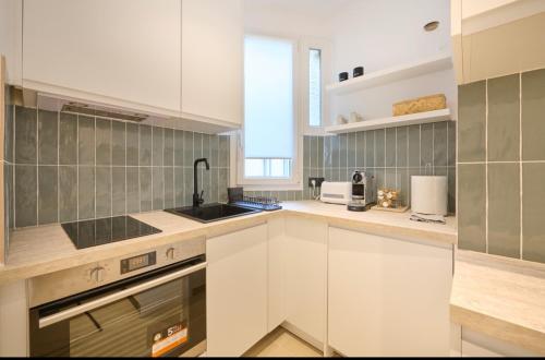 une cuisine avec des armoires blanches et un évier dans l'établissement Eiffel Appartement, à Paris