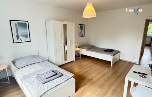 a bedroom with two beds and a table and a desk at BEGE APARTMENTS Corporate Hub in Lüdenscheid