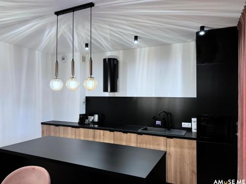 a kitchen with a black counter and some lights at AMuSE ME in Kielce