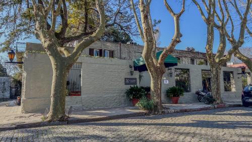 a building on the side of a street with trees at Viajero Colonia Hostel in Colonia del Sacramento