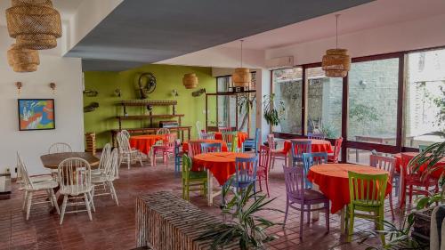 a restaurant with colorful tables and chairs and windows at Viajero Colonia Hostel in Colonia del Sacramento