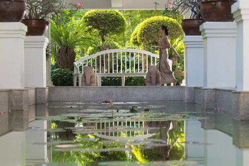 a woman standing next to a pond of water lilies at Mandarin Oriental, Bangkok in Bangkok