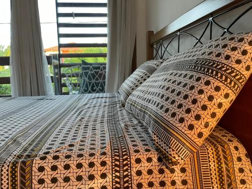 a bed with an orange and gray comforter and a window at Hospedaria Canto Itaúnas in Itaúnas