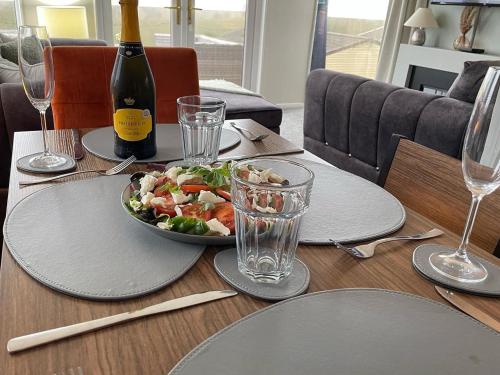 a table with a plate of salad and a bottle of wine at Ribble Valley Lodge Retreat in Gisburn
