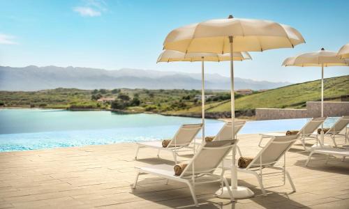 a group of chairs and umbrellas next to a pool at Aminess Style Glamping Villas & Holiday Homes Avalona in Povljana