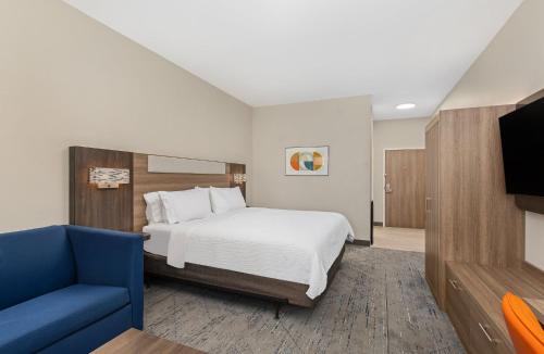 a hotel room with a bed and a blue chair at Holiday Inn Express Hurricane Mills Waverly by IHG in Hurricane Mills