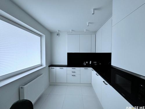 a white kitchen with white cabinets and a window at AMuSE ME in Kielce
