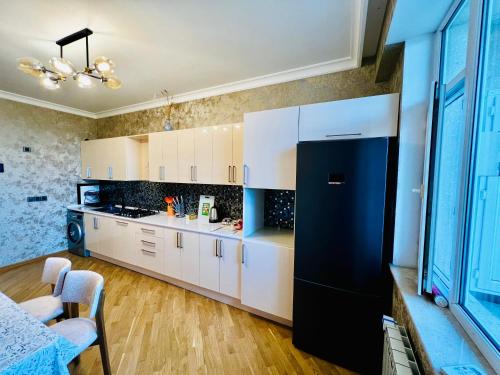 a kitchen with white cabinets and a black refrigerator at Secrets Apartment in Baku