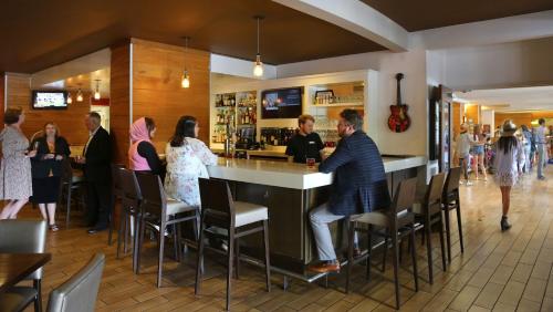 a group of people standing around a bar in a restaurant at Holiday Inn Nashville - Vanderbilt - Dwtn by IHG in Nashville