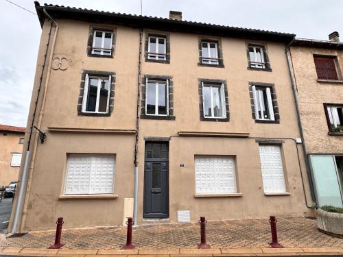 - un grand bâtiment avec une porte et des fenêtres noires dans l'établissement La maison castelpontine studio 2, à Pont-du-Château