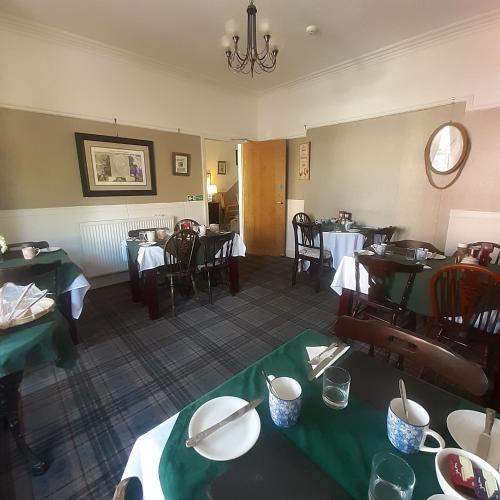 a dining room with tables and chairs and a chandelier at The Merrydale Guest House in Llandudno