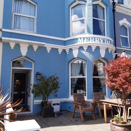 a blue building with chairs in front of it at The Merrydale Guest House in Llandudno