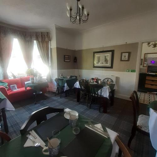 a living room with tables and a red couch at The Merrydale Guest House in Llandudno