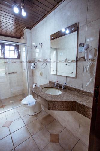 a bathroom with a sink and a toilet and a mirror at Filadélfia Hospedagens e Eventos in São Bento do Sul