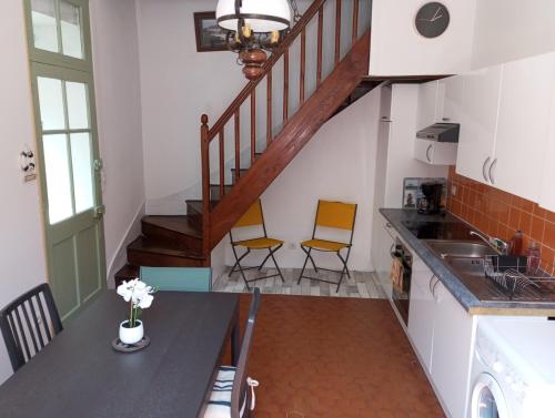 une cuisine avec deux chaises et une table ainsi qu'un escalier dans l'établissement Le Cocon de Renée, Maison atypique en ville close de Concarneau, à Concarneau